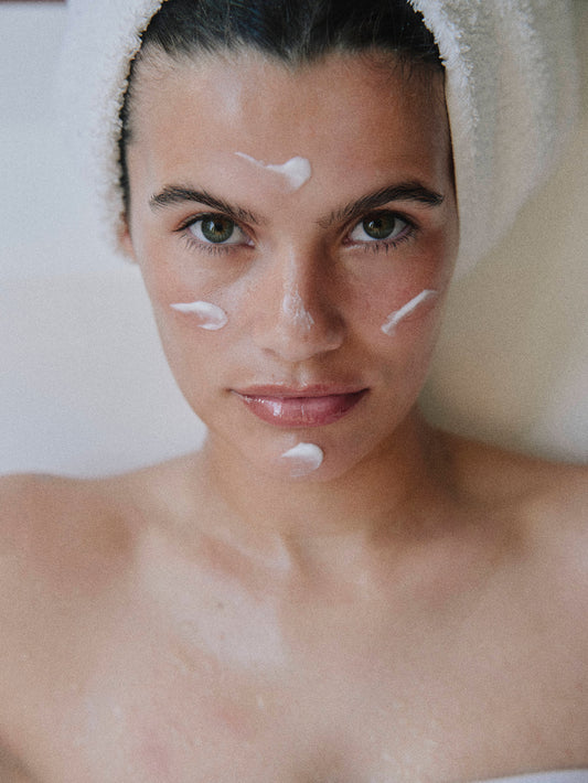 woman in white towel with moisturizer on her face for LADA beauty skincare brand